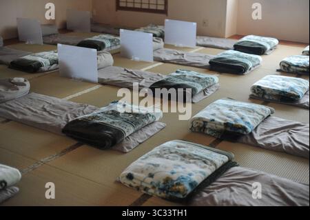 Interno di una tradizionale camera d'hotel in Giappone con materassi e cuscini futon e cuscini e tappeti tatami su un pavimento Foto Stock
