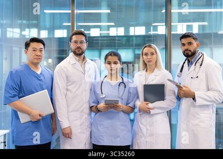 Un team eterogeneo di professionisti sanitari che si uniscono, rappresentando unità e competenza in un ambiente medico moderno. Foto Stock