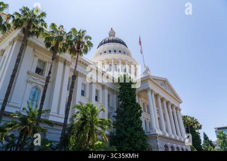 Sacramento, California, USA - 21 giugno 2025: Edificio storico del Campidoglio della California, vista laterale, con bandiere californiane, statunitensi e bandiera lgbtq Foto Stock