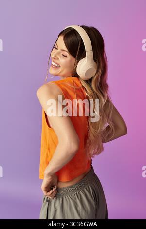 Una giovane donna ama la musica mentre abbraccia un'atmosfera estiva spensierata su uno sfondo colorato Foto Stock