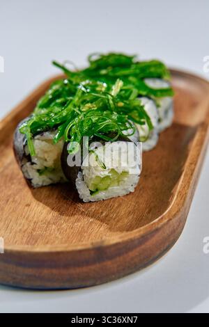 Deliziosi sushi Rolls preparati con ingredienti freschi e conditi con una vivace alghe marine su un piatto di legno naturale per una delizia culinaria Foto Stock