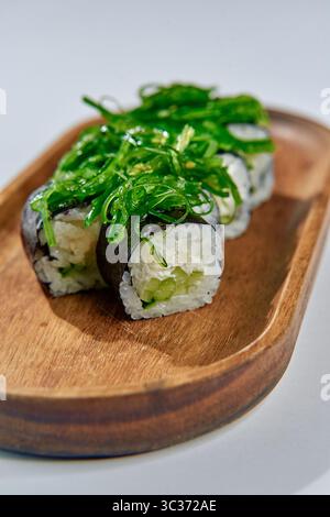 Deliziosi sushi Rolls preparati con ingredienti freschi e conditi con una vivace alghe marine su un piatto di legno naturale per una delizia culinaria Foto Stock