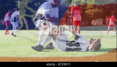 Due giocatori con maglie bianche che aiutano il compagno di squadra durante le esercitazioni di calcio, con coni di allenamento arancioni Foto Stock