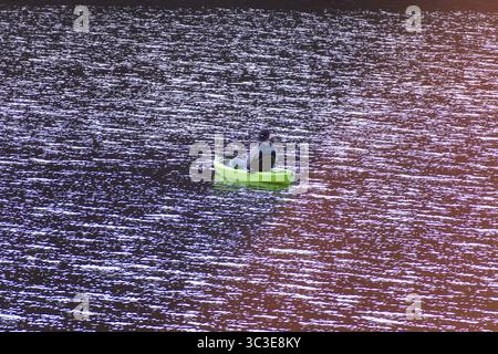 Oakley, Utah - 20 luglio 2025: Un uomo pesca da un kayak verde brillante sulla Smith and Morehouse Reservoir, circondato da acque calme e paesaggi alpini. Foto Stock