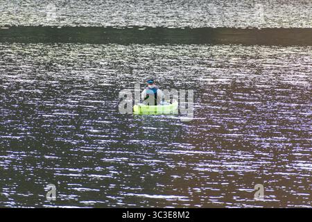 Oakley, Utah - 20 luglio 2025: Un uomo pesca da un kayak verde brillante sulla Smith and Morehouse Reservoir, circondato da acque calme e paesaggi alpini. Foto Stock