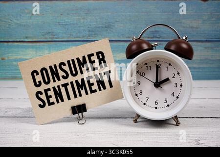 Testo del sentimento del consumatore scritto su carta con sveglia su sfondo di legno Foto Stock