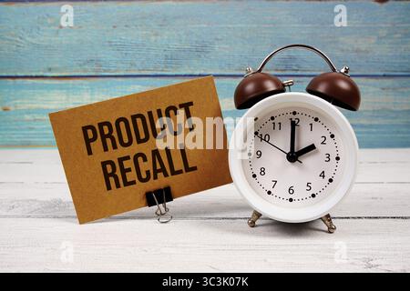 Testo del richiamo del prodotto scritto su carta con sveglia su sfondo in legno Foto Stock