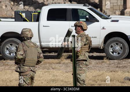 Il personale militare con equipaggiamento mimetico mobilita le attrezzature a bordo di un camion in una zona di addestramento tattico. Foto Stock