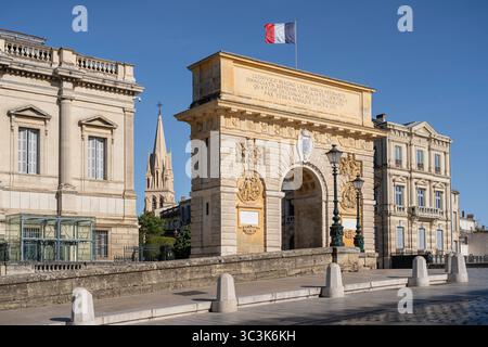 Vista panoramica della storica porte du Peyrou, arco di trionfo con bandiera francese e campanile della chiesa di Sant'Anna, famosi monumenti di Montpellier, Francia Foto Stock