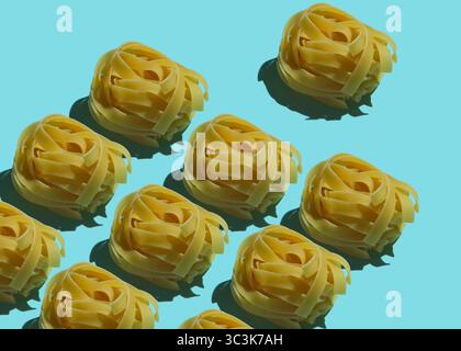 Palline di tagliatelle asciutte su sfondo blu. Shot di cibo minimalista Foto Stock