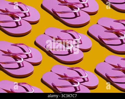 Vacanza al mare, sfondo estivo. Stile pop art. Molte infradito rosa su sfondo giallo. Foto di moda con ombre. Foto Stock