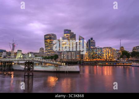 Vista dello skyline della città, della HMS Belfast e del Tamigi al tramonto, Londra, Inghilterra. Scene notturne di architettura. Foto Stock