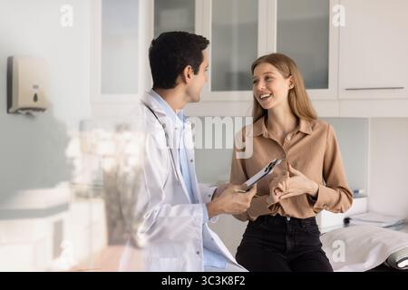 Felice giovane paziente di vent'anni che parla con un medico maschile Foto Stock