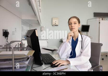 Medico sicuro che posa per il ritratto del profilo al computer in clinica Foto Stock