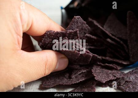 Una vista di una mano che afferra delle tortilla di mais blu. Foto Stock