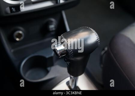 Pomello del cambio automatico in pelle nell'abitacolo della vettura in nero per la guida e l'accelerazione. Immagine astratta della velocità elevata. Warran Foto Stock
