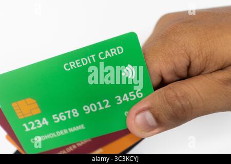 Carta di credito verde tenuta in mano su sfondo bianco. Foto Stock
