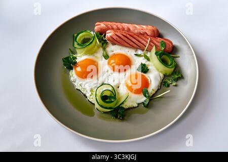 Abbondante piatto per la colazione con uova, salsicce e verdure fresche per un delizioso inizio di giornata Foto Stock