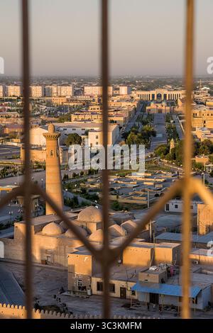 Khiva, Uzbekistan - 12 luglio 2024: Veduta aerea di un minareto che domina la città di Khiva, con la stazione ferroviaria visibile sullo sfondo lontano Foto Stock
