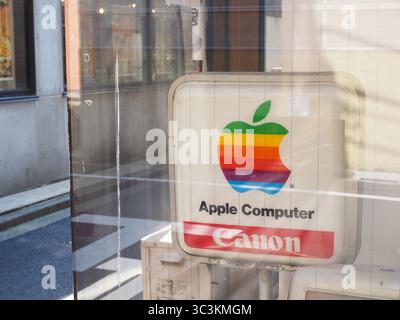 TOKYO, GIAPPONE - 24 luglio 2025: Un cartello con un vecchio logo Apple e un logo Canon nella vetrina di un negozio nell'area Akihabara di Tokyo. Foto Stock