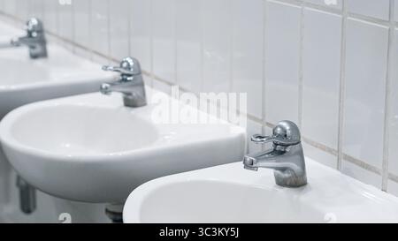 Igienico interno bianco per servizi igienici con lavandini multipli per lavare le mani Foto Stock
