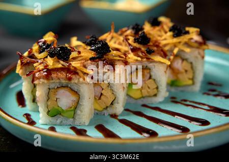 Una deliziosa disposizione di Sushi Rolls presentati ad arte su un vibrante piatto blu, che mette in evidenza ingredienti unici ed eleganti decorazioni in una cucina Foto Stock