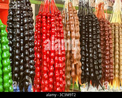 Un colorato e appetitoso spettacolo di tradizionali dolci georgiani churchkhela appesi in un mercato. Le caramelle a forma di candela, fatte di noci Foto Stock