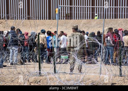 I migranti si riuniscono al recinto di frontiera di Ciudad Juarez, supervisionato dalla sicurezza. Foto Stock
