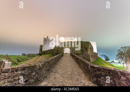 Il cancello del re, il castello di dover di notte. Il ponte di pietra che porta al cancello e dietro le mura interne di bailey e il mastio, la grande Torre. Stemmi sopra il cancello Foto Stock