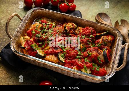 Delizioso salmone al forno servito con un assortimento di verdure fresche, il tutto soffocato generosamente in una salata salsa di pomodoro. Perfetto per un sapore sano Foto Stock