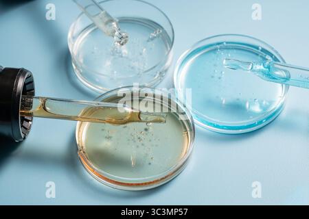 Una vista ravvicinata mostra una pipetta cosmetica appoggiata su capsule di Petri riempite di liquido. Questa immagine evidenzia gli strumenti di laboratorio utilizzati per la cura della pelle Foto Stock