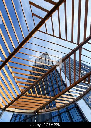 Una vista accattivante dell'architettura moderna che mostra design innovativo e forme geometriche in un ambiente urbano, mescolando vetro e acciaio con legno Foto Stock
