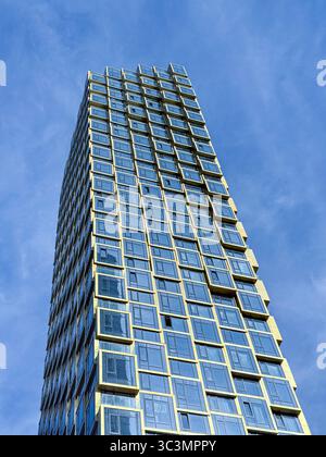 Un moderno grattacielo con una suggestiva facciata geometrica si erge su un cielo blu limpido. Questa imponente struttura presenta un design architettonico contemporaneo Foto Stock