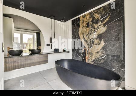 Un lussuoso bagno moderno con una elegante vasca nera, finiture eleganti e finiture eleganti, a creare un'atmosfera sofisticata e rilassante Foto Stock