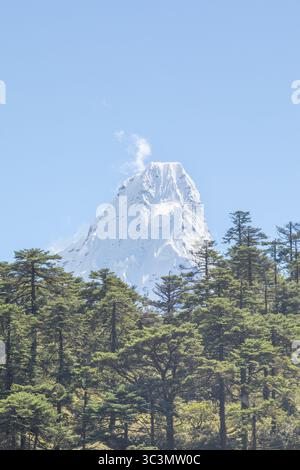 Ama Dablam, innevata, sorge maestosamente su lussureggianti foreste verdi nella regione del Nepal, offrendo una vista mozzafiato perfetta per gli avventurieri e la natura Foto Stock