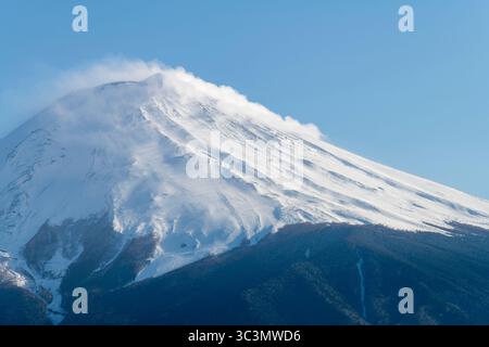 Primo piano del cono simmetrico innevato dello stratovulcano attivo Mt. Fuji con alcune nuvole sulla cima del vulcano Foto Stock