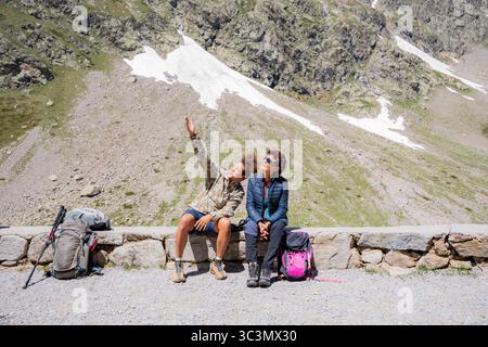In una giornata di sole, con la famiglia che desidera fare un'escursione, circondata da aspri paesaggi rocciosi e da lontane cime innevate. Si siedono su una sporgenza di pietra, prendendo il Foto Stock