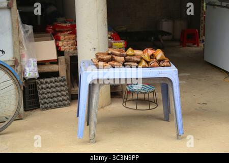 Un semplice negozio di alimentari del gruppo etnico thailandese a Dien Bien, Vietnam, con torte di riso appiccicose esposte sul tavolo e alcune uova, torte Foto Stock