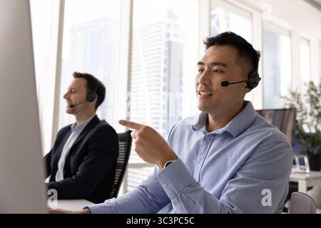 Giovane uomo professionale asiatico che assiste al cliente da remoto Foto Stock