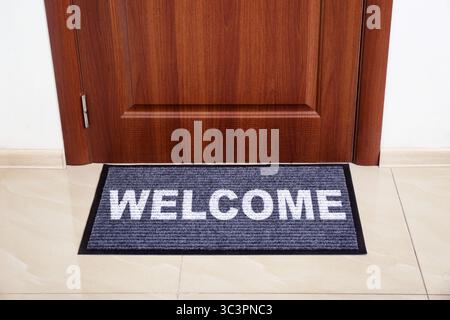 Tappetino di benvenuto sul pavimento vicino alla porta d'ingresso Foto Stock
