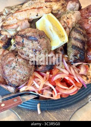 Primo piano di un tradizionale piatto di carne alla griglia greco servito ad Atene, Grecia, con souvlaki, polpette, salsicce, pollo alla griglia e un lato di Foto Stock