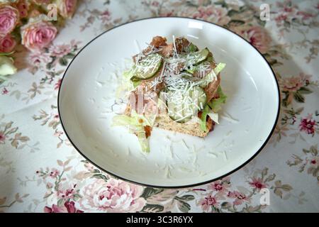 Un delizioso piatto di insalate con lattuga fresca, proteine magre, crocchette e formaggio grattugiato su una base di pane leggermente tostata, perfetto per un'eatina sana Foto Stock