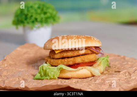 hamburger succoso con cotoletta di pollo. Cotoletta di pollo succosa con formaggio fuso croccante, verdure fresche (pomodoro, insalata, cipolla rossa) tra panini morbidi Foto Stock