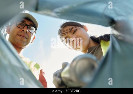 Giovane ispanico uomo e donna che raccolgono il cestino durante l'attività di pulizia all'aperto Foto Stock