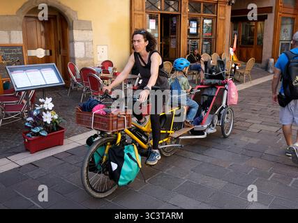 Donna madre e figli in bicicletta e rimorchio ad Annecy, Francia Foto Stock