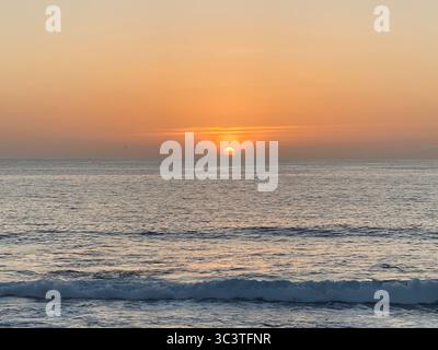Uno splendido tramonto sull'oceano Atlantico, con le onde che rotolano dolcemente verso la riva. Foto Stock