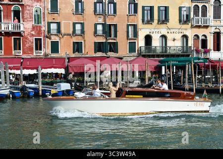 Taxi boat con turisti sul Canal grande, di fronte al lungomare di Riva del Vin in estate, Venezia, Veneto, Italia Foto Stock