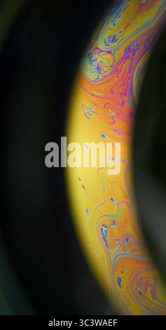 Liquido a benzina. Pittura mistica. Colorato Arch emulsione arancio giallo olio consistenza miscelazione colorante. Sfondo sfocato luminoso, spazio notturno nero. Foto Stock