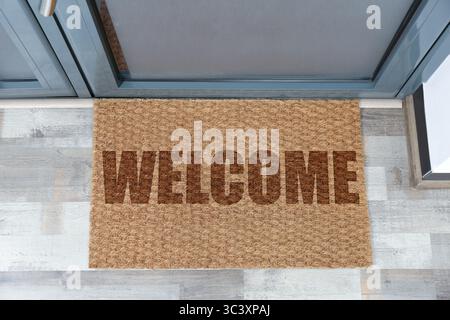 Tappetino di benvenuto sul pavimento vicino alla porta d'ingresso, vista dall'alto Foto Stock