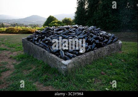 Una pila di bottiglie di vetro vintage poggia su una piattaforma di pietra con le lussureggianti colline del nord del Portogallo in lontananza Foto Stock